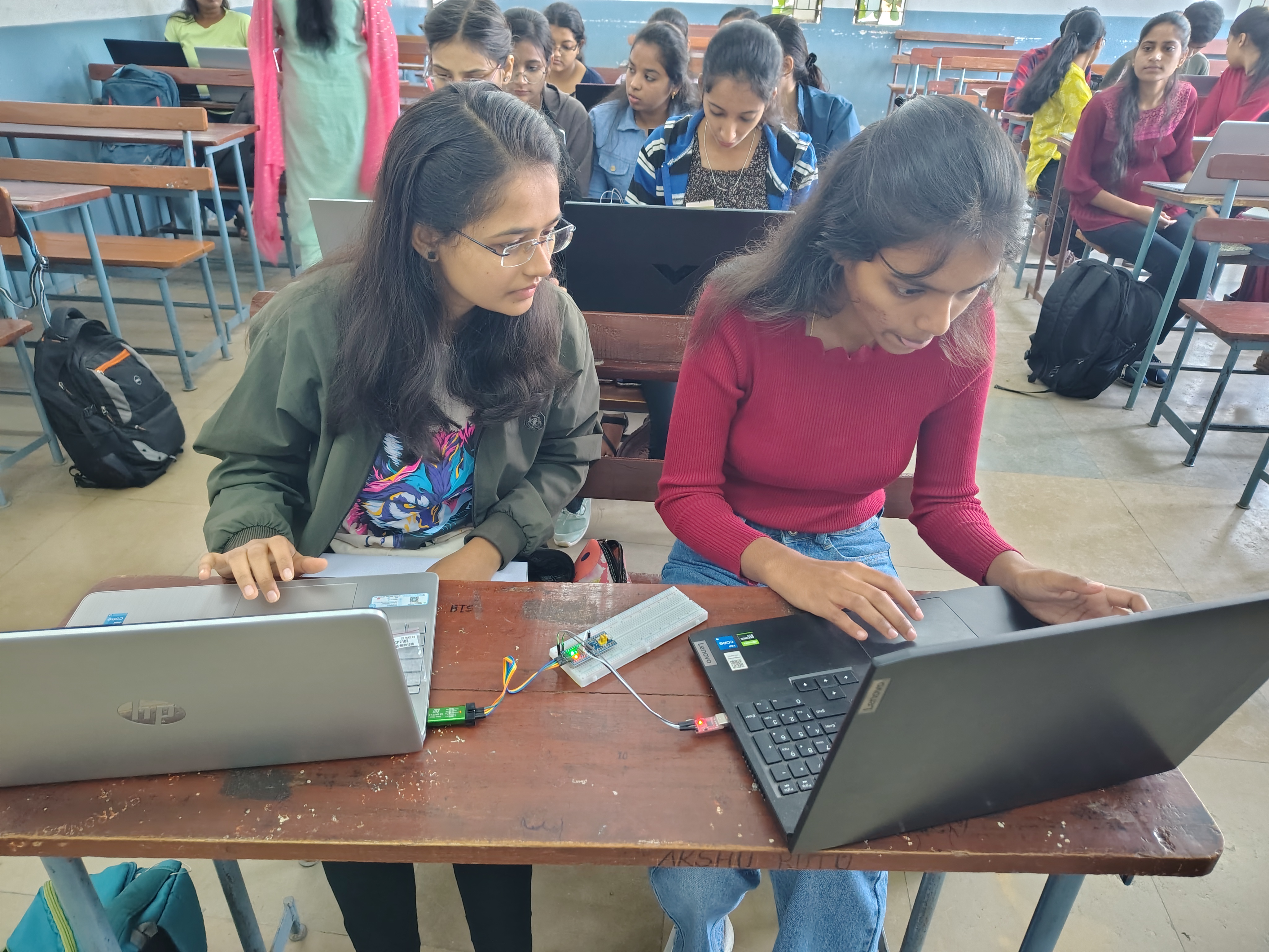 Students working with STM32 hardware and laptops during a practical embedded systems workshop